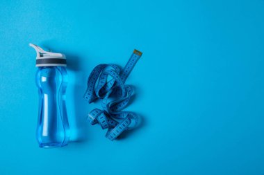 spor şişe ve ölçüm bandı izole mavi, minimalist kavramı üzerinde üstten görünüm 
