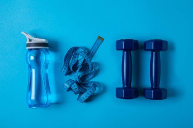 spor şişe su, ölçme bant ve mavi izole dumbbells ile yukarıdan görüntülemek 