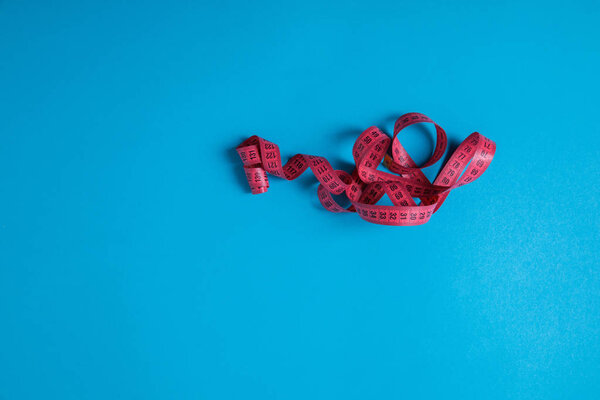 elevated view of pink measuring tape isolated on blue, minimalistic concept 