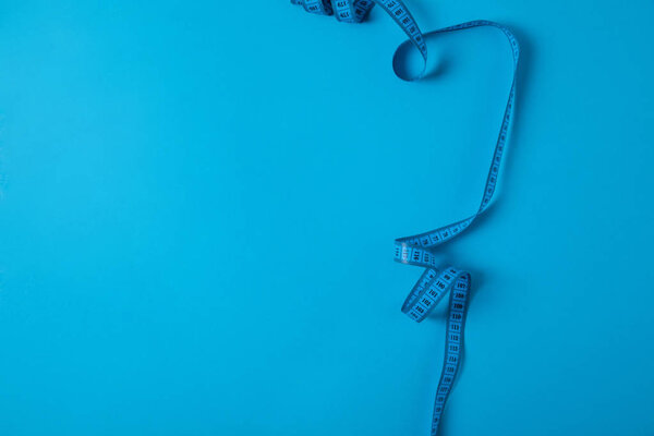 top view of measuring tape isolated on blue, minimalistic concept 