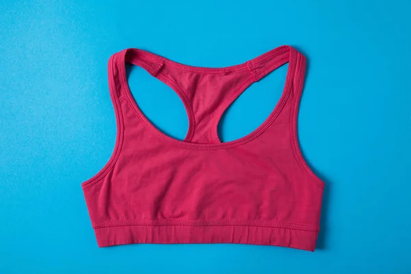 平躺与粉红色的运动胸罩隔离在蓝色 简约的概念 — 图库照片