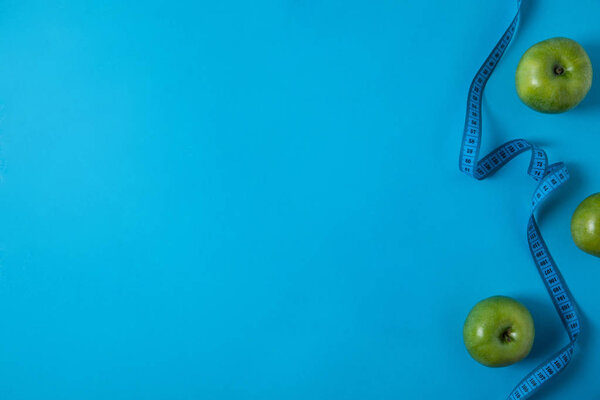 view from above of green apples and measuring tape isolated on blue 