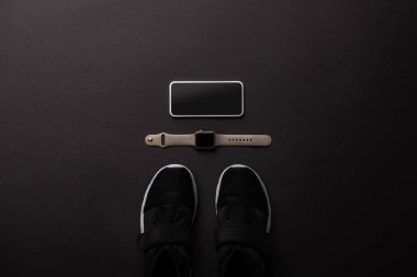 düz lay görücü usulü smartphone, smartwatch ve izole siyah, minimalist kavramı üzerinde ayakkabı ile 