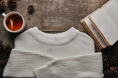 beyaz kazak, çam kozalakları, boş defter ve çay ahşap yüzey üzerinde düz lay