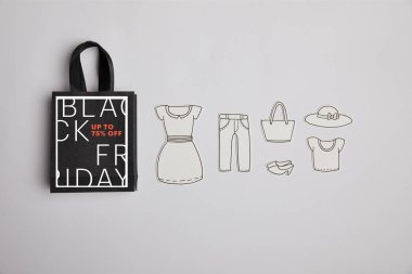 kağıt torba siyah Cuma satışı işareti ve kağıt giysileri ile üstten görünüm gri arka plan üzerinde