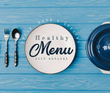 Top mavi masada çatal, kaşık ve plakaları görünümü sağlıklı menü yazı