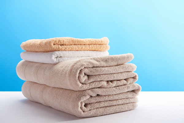 close-up view of stacked clean towels on white table on blue