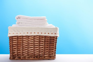 Çamaşır sepeti temiz yumuşak havlu ile mavi arka plan üzerinde görmek