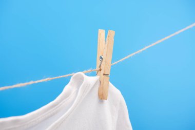 close-up view of clean white t-shirt with clothespin hanging on rope isolated on blue  clipart