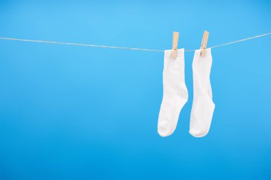 close-up view of clean white socks hanging on rope isolated on blue  clipart