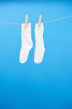 close-up view of clean white socks hanging on clothesline isolated on blue  clipart