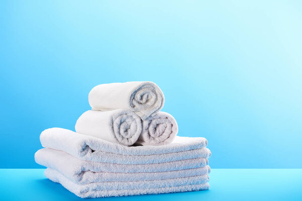 rolled and stacked clean white towels on blue 