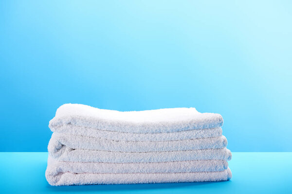 pile of clean soft white towels on blue background