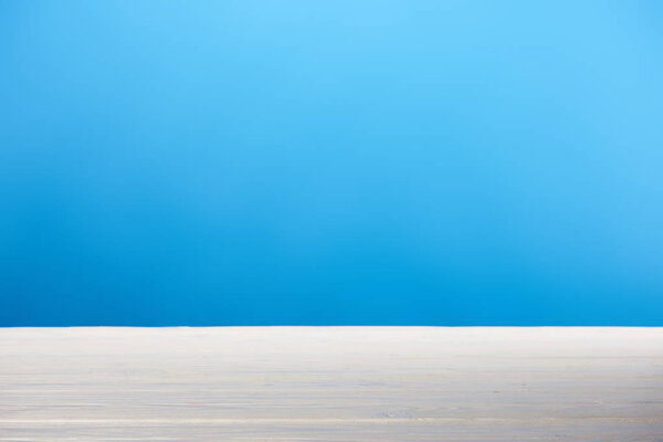 empty white wooden surface and bright blue background