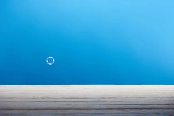 青の背景にシャボン玉と白の木製表面 — ストック写真