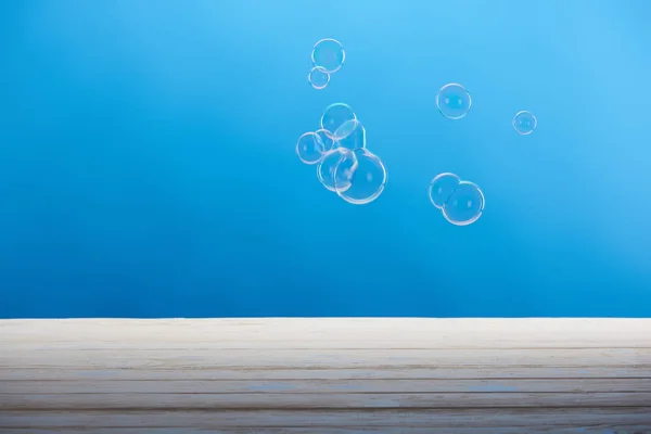 soap bubbles and white wooden surface on blue background