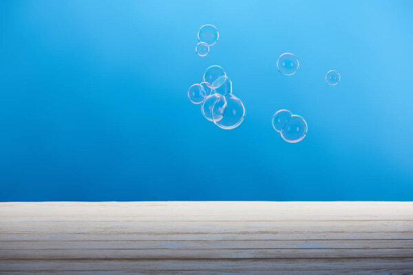 soap bubbles and white wooden surface on blue background