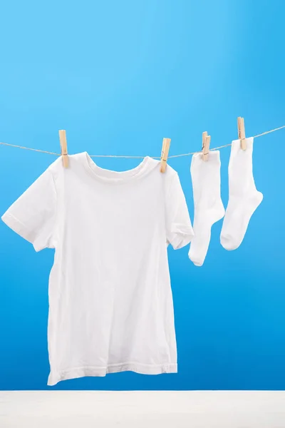 干净的白色 T恤和袜子挂在蓝色的晾衣绳上 — 图库照片