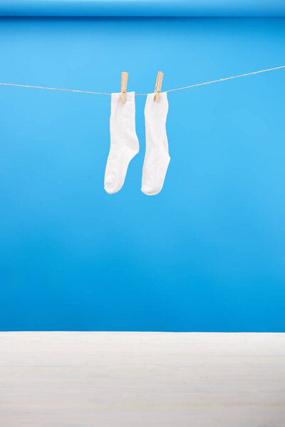 clean white socks hanging on clothesline on blue