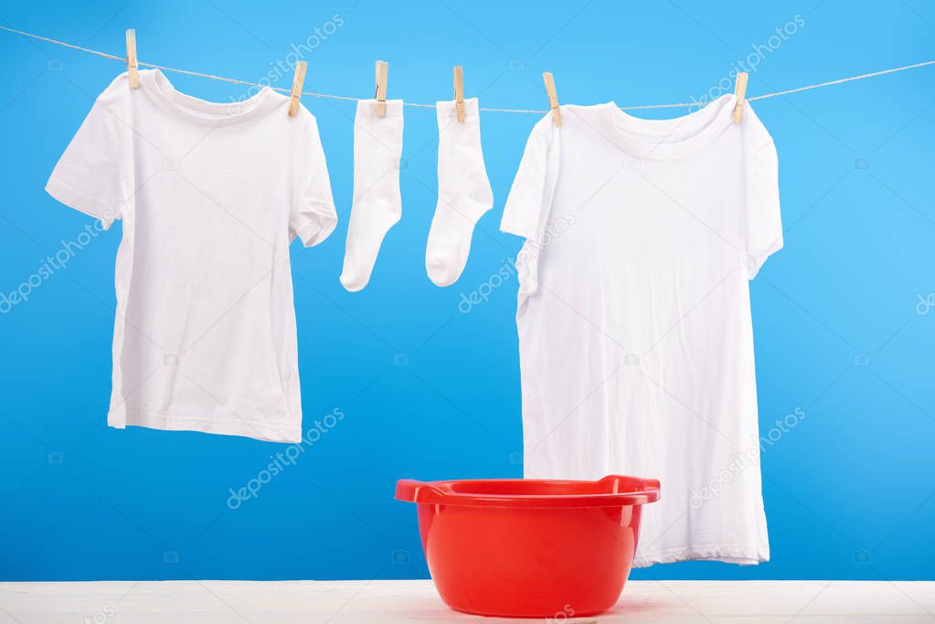 red basin and clean white clothes hanging on clothesline on blue 