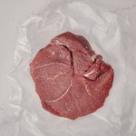 Ansicht von rohem Frischfleisch auf zerknülltem Kochpapier mit weißem Hintergrund