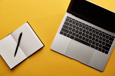 sarı yüzeyi açık defter ve laptop üstten görünüm