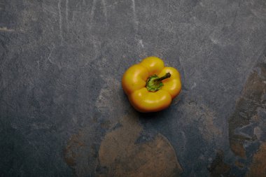 top view of yellow bell pepper on grey marble background clipart