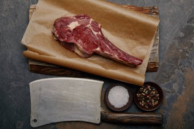 top view of raw rib eye steak on baking paper with butcher knife, spices  clipart