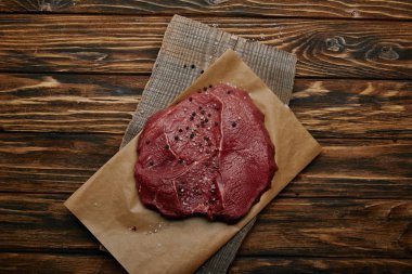 top view of raw fresh meat on baking paper on wooden background clipart