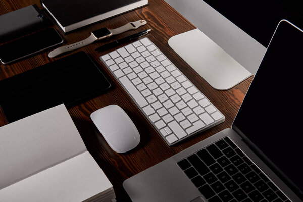 современное рабочее место с различными устройствами на деревянном столе
