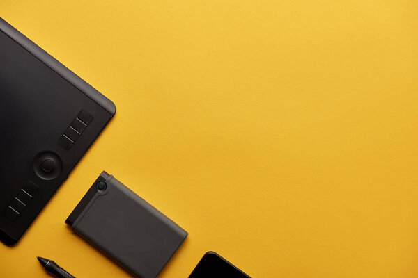 top view of graphics tablet and portable hdd on yellow surface