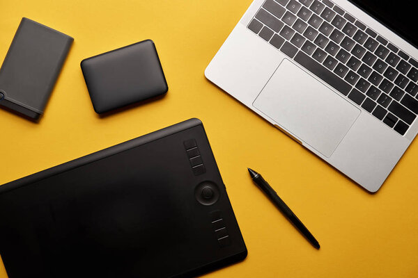 top view of different graphic designer gadgets on yellow surface