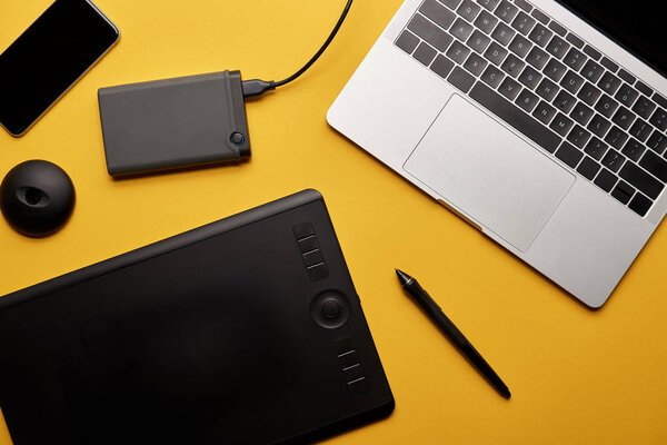 top view of various graphic designer gadgets on yellow surface