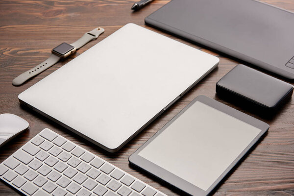 close-up shot of various wireless gadgets and graphics tablet on wooden desk