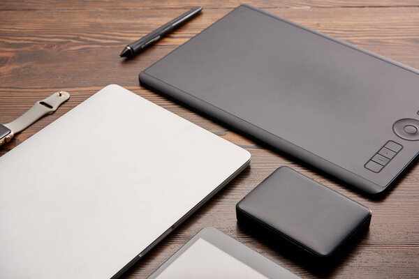 close-up shot of various wireless devices and graphics tablet on wooden desk