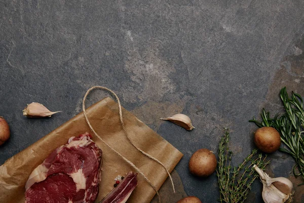 灰色の背景にジャガイモと紙を焼く生肉ステーキのトップ ビュー — ストック写真