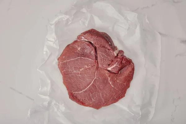 白い背景紙を丸めて調理に新鮮な生肉のトップ ビュー  — 無料ストックフォト