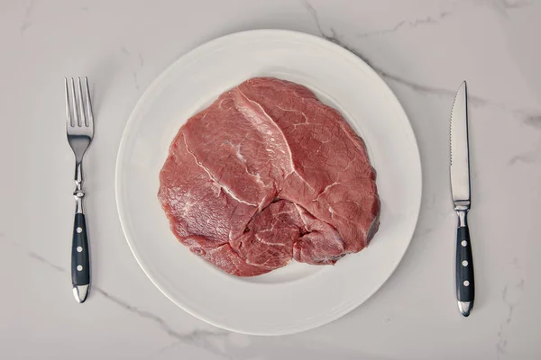 Вид Свежее Сырое Мясо Тарелке Кухонными Столовыми Приборами Белом Фоне — стоковое фото