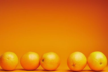 close-up view of fresh ripe oranges on orange background clipart