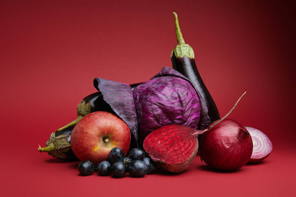 fresh ripe organic apple, grapes, onions, beetroot, cabbage and eggplants on red 
