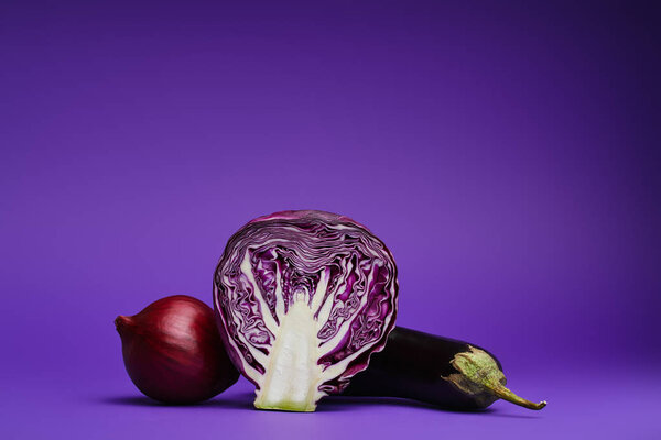 close-up view of sliced cabbage, onion and eggplant on purple background