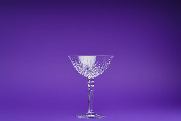 крупным планом один пустой стакан на фиолетовом фоне
