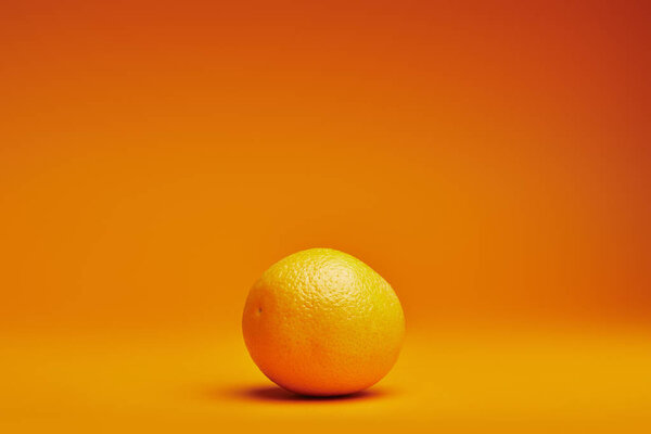 close-up view of fresh ripe whole orange on orange background 