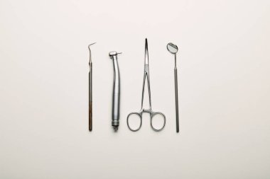 flat lay with stainless dental instruments arranged on white tabletop, dentistry concept clipart