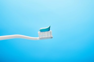 close up view of toothbrush with paste on blue backdrop clipart