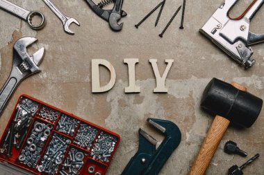 Top view of do it yourself sign and various carpentry tools arranged on old  surface background  clipart