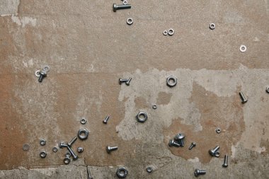 Top view of screws and bolts scattered on the background of old  surface clipart