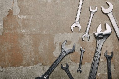 Top view of different wrenches and one monkey wrench on the background of old  surface clipart