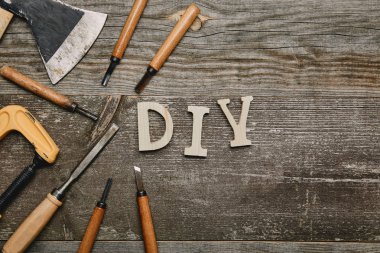 Top view of different carpentry tools and diy sign on wooden background clipart