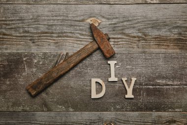 Top view of rusty hammer and diy sgn on wooden background clipart